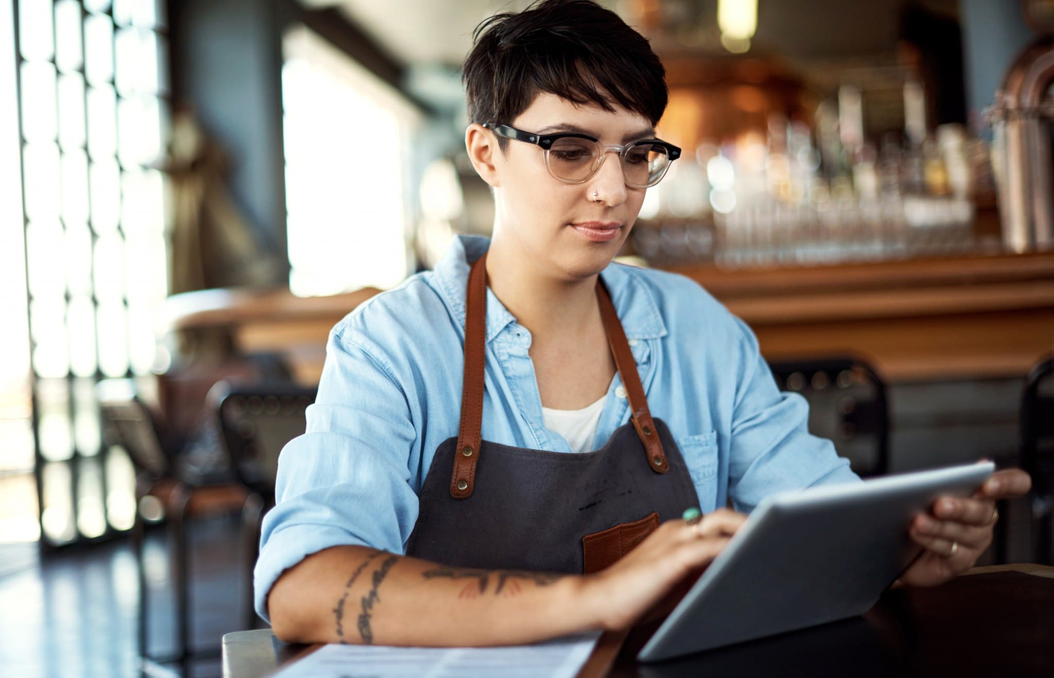 A woman working in a restaurant takes inventory on a tablet.