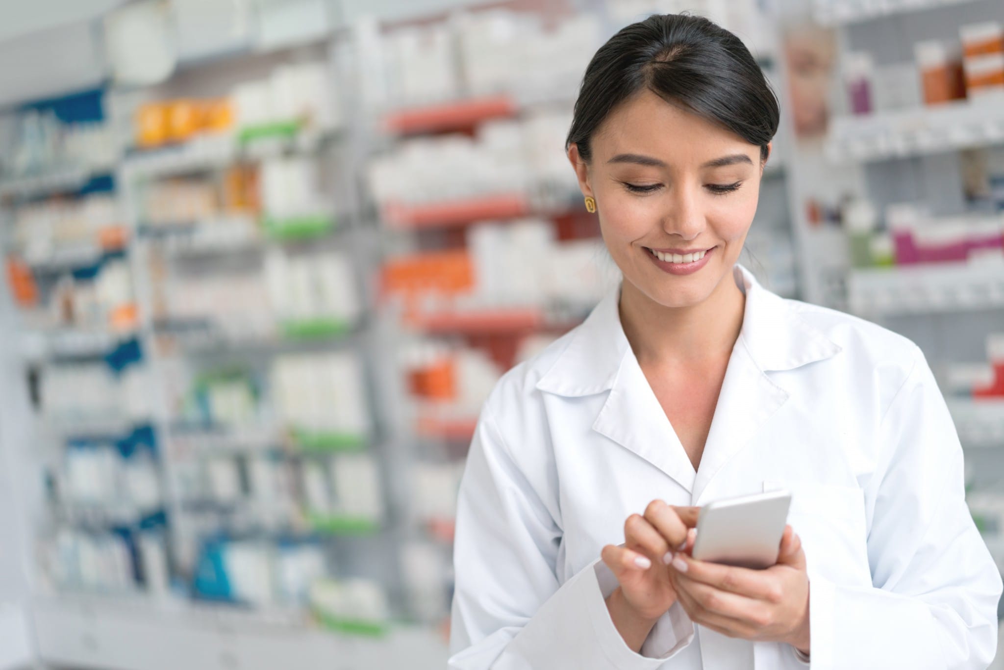 a female healthcare worker uses a phone with medical storage in background.