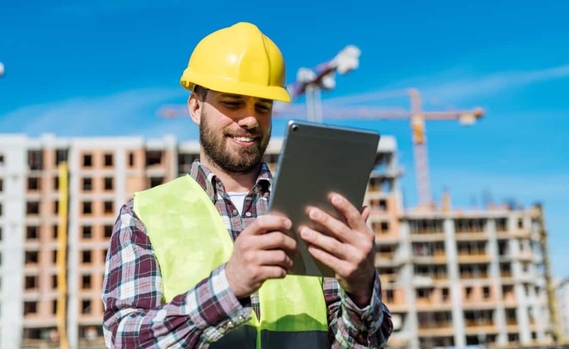 A construction worker uses a construction app on a job site.